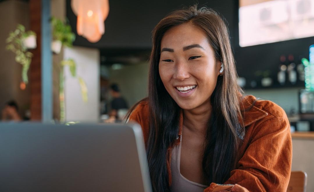 a woman smiling while working on laptop